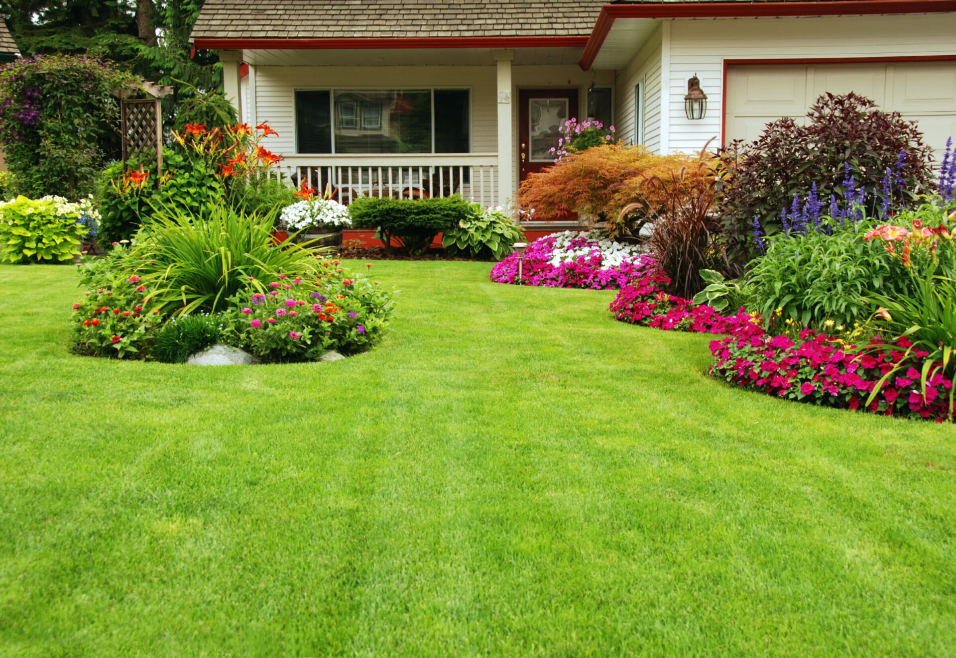 Lush garden with vibrant flowers, neat green lawn, and cozy house porch. Colorful plants create a welcoming, serene home entrance atmosphere.