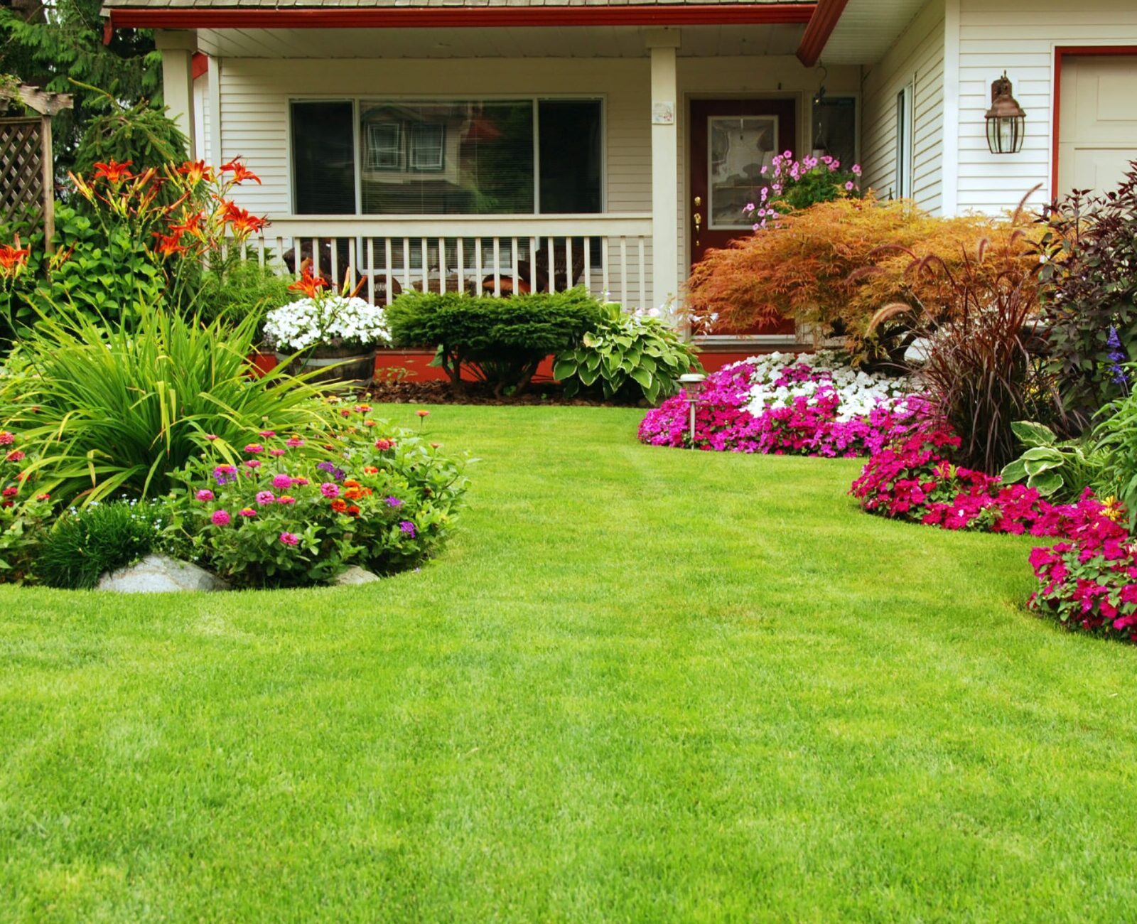 Lush garden with vibrant flowers, neat green lawn, and cozy house porch. Colorful plants create a welcoming, serene home entrance atmosphere.