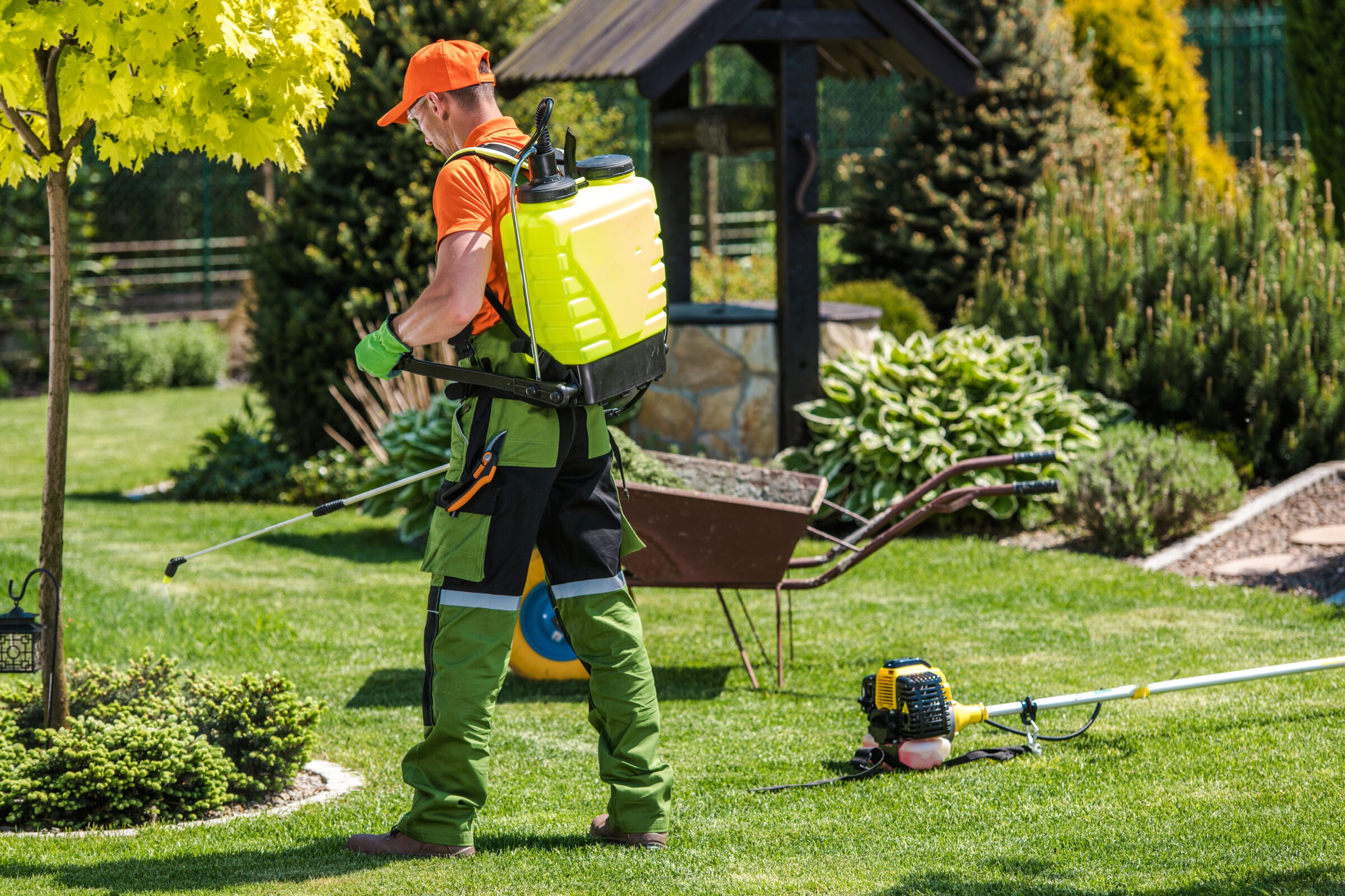 A person in orange and green clothing tends a garden with a yellow sprayer, surrounded by lush greenery and gardening tools.