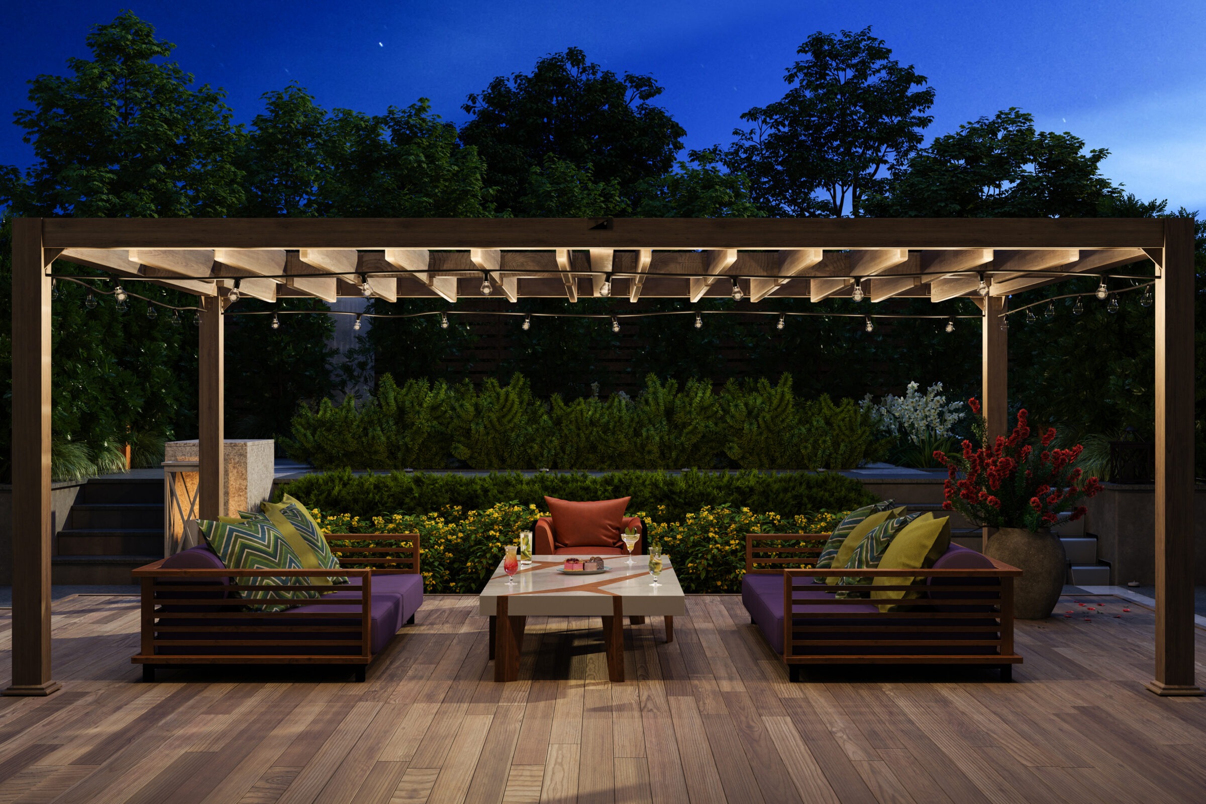 A cozy outdoor seating area under a wooden pergola adorned with string lights, surrounded by lush greenery and vibrant flowers at night.