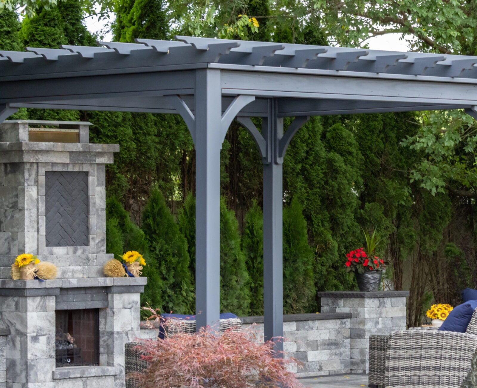 A well-maintained garden with a pergola, outdoor seating, fireplace, decorative vases, and plants, creating a relaxing and inviting atmosphere.
