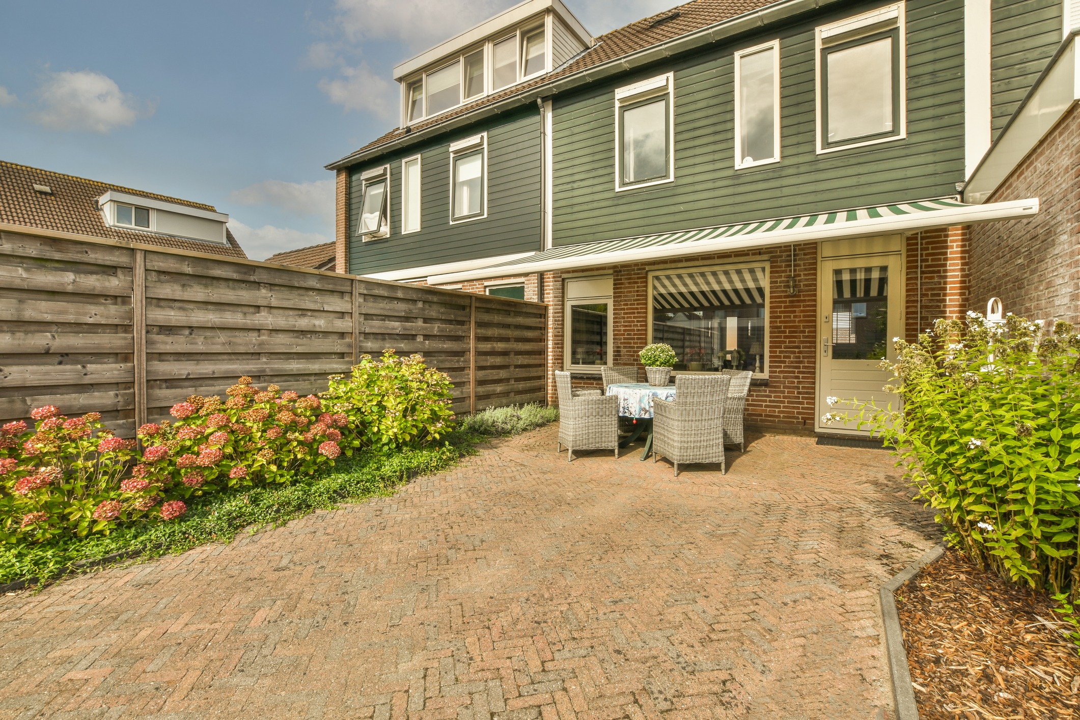Neat powerful patio with sitting area and small garden near wooden fence