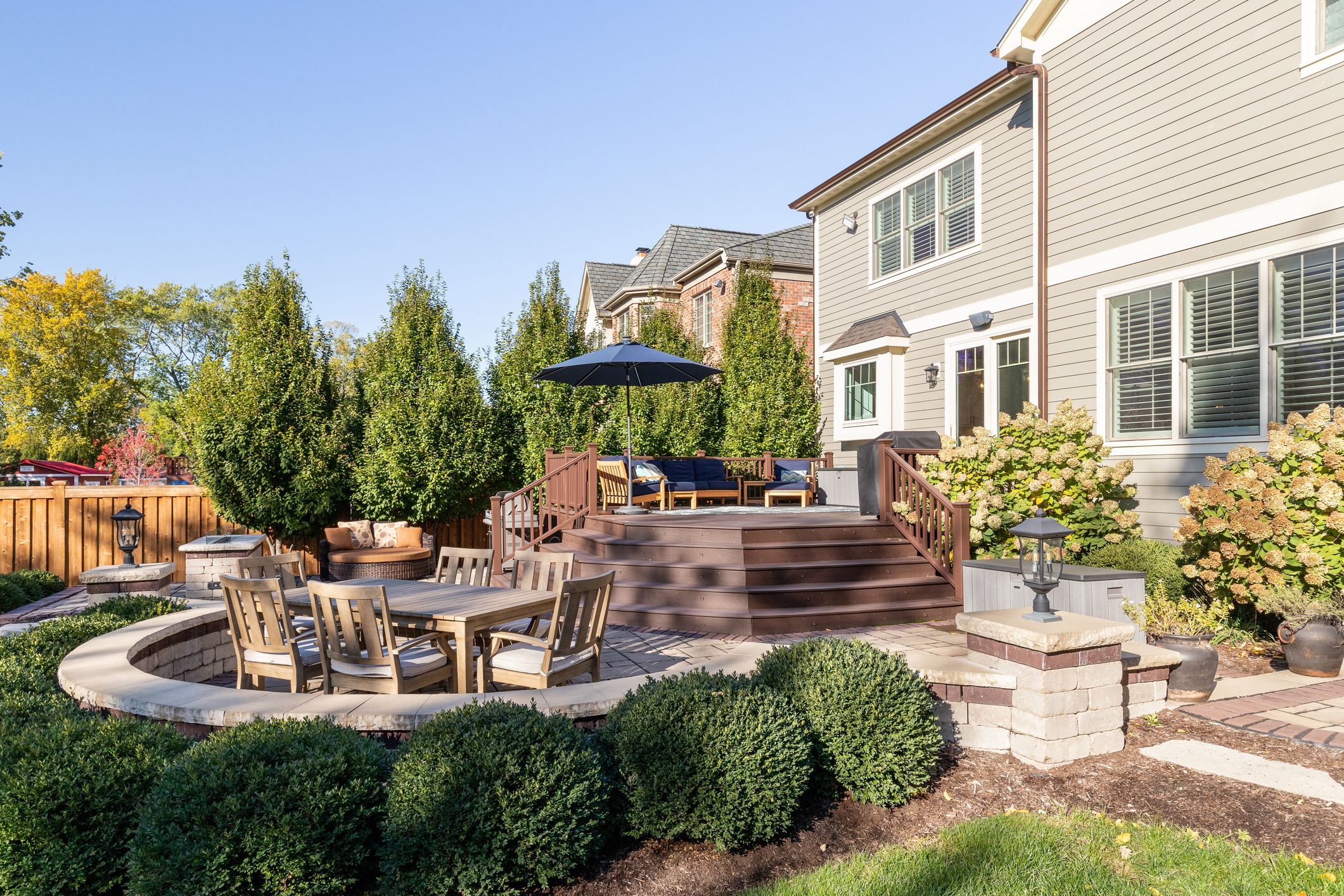 Backyard of a luxury modern farmhouse with a multiple level patio with different seating areas.