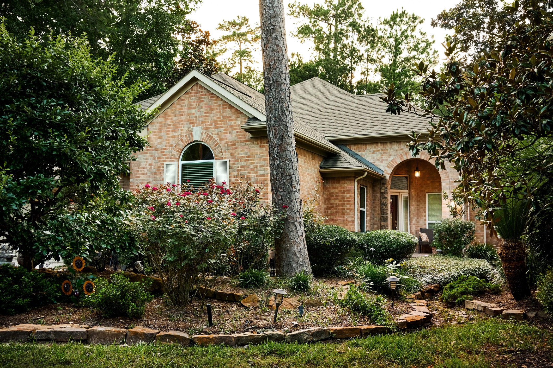 Beautiful exterior of a stone and brick home nestled among a lush garden with trees