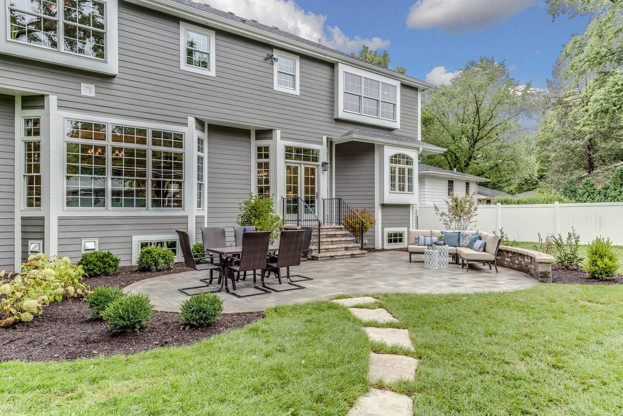 Backyard patio with dining set, stone seating wall, and stepping stone pathway
