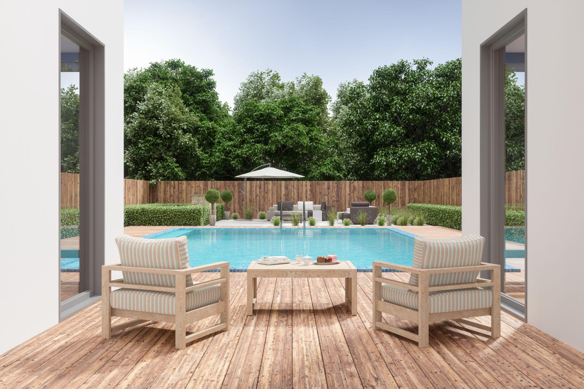 Backyard pool and wood deck with outdoor lounge chairs and privacy fence