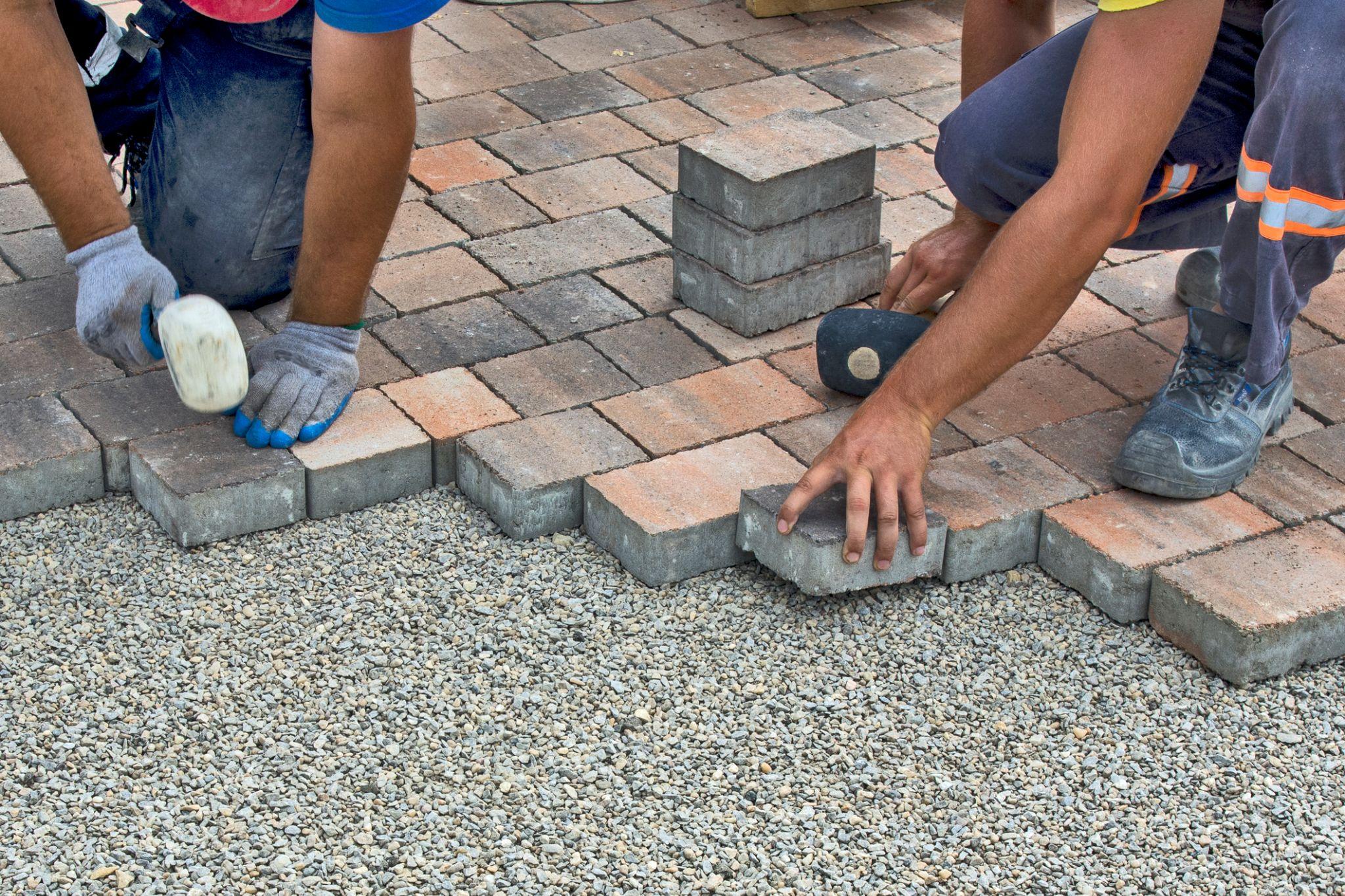 Crew installing brick pavers on a gravel base