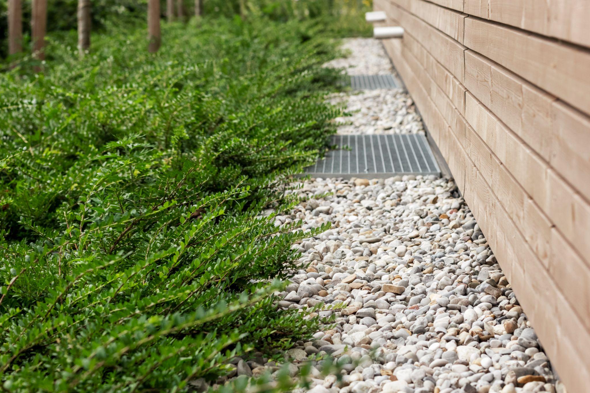 Gravel drainage channel with linear drain grate along retaining wall base