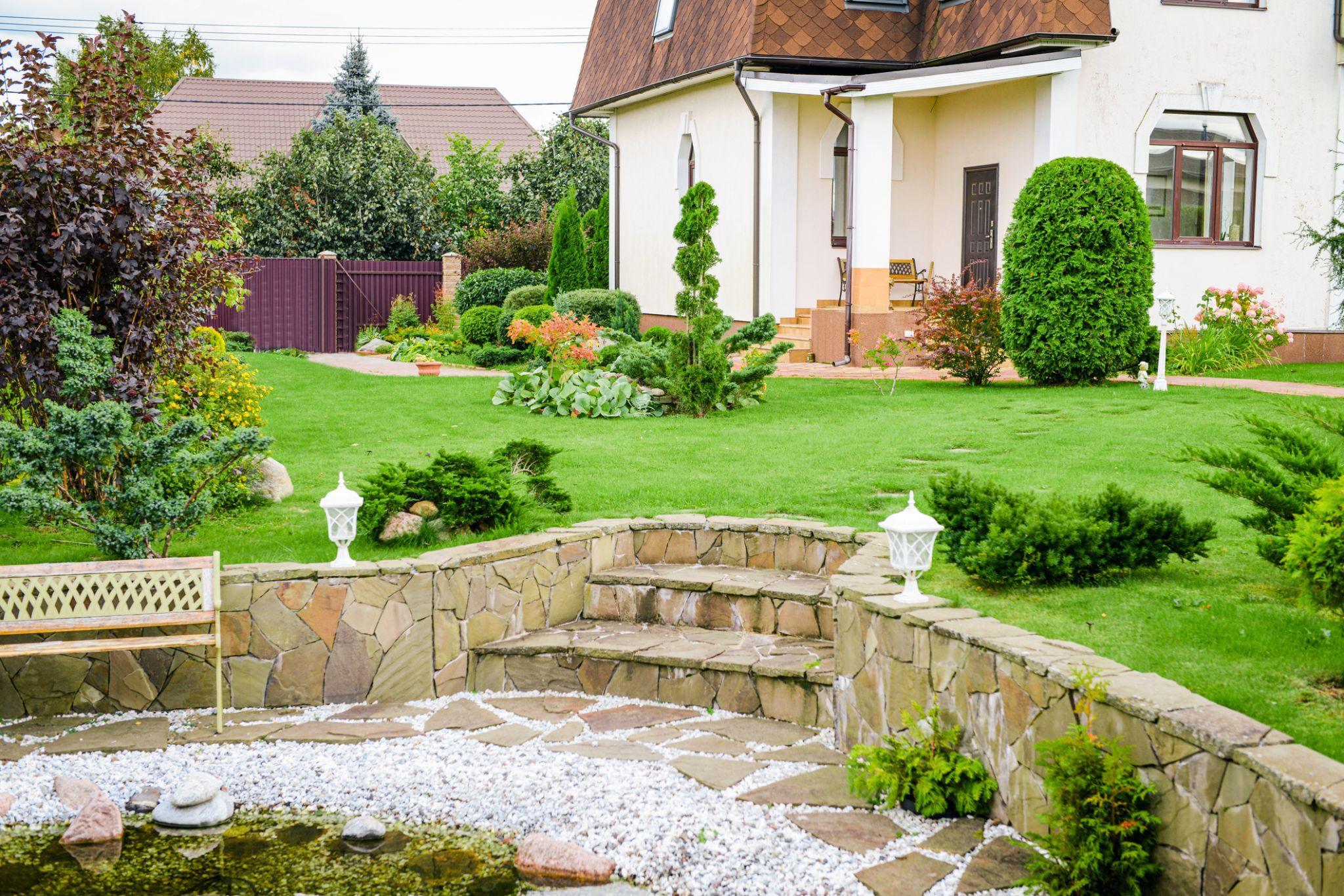 Landscaped front yard with stone retaining wall, steps, and manicured lawn