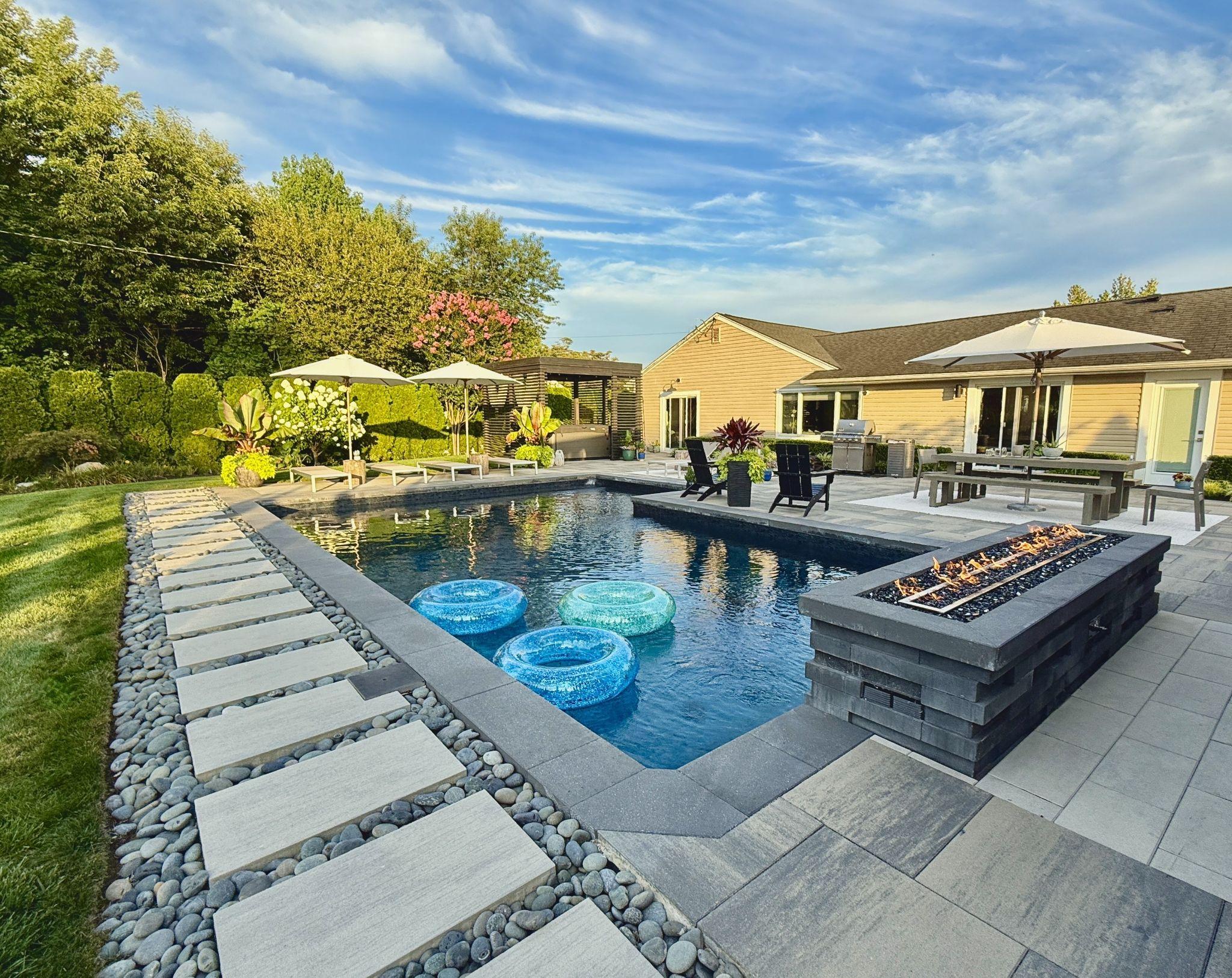 Modern backyard pool with fire feature, paver patio, and outdoor lounge area