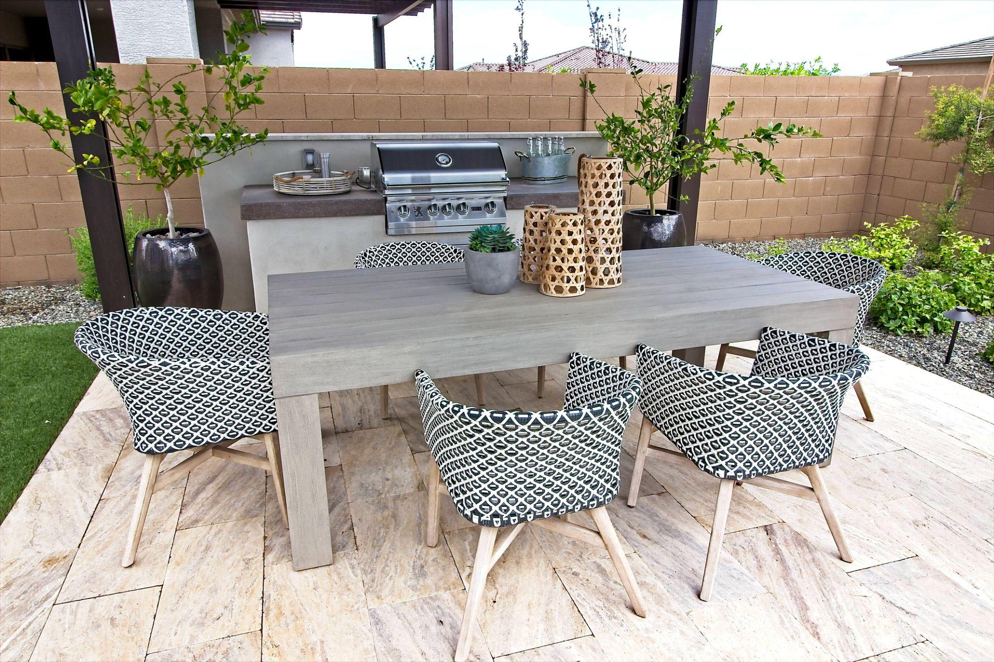 Outdoor dining area with built-in grill, stone tile patio, and pergola cover