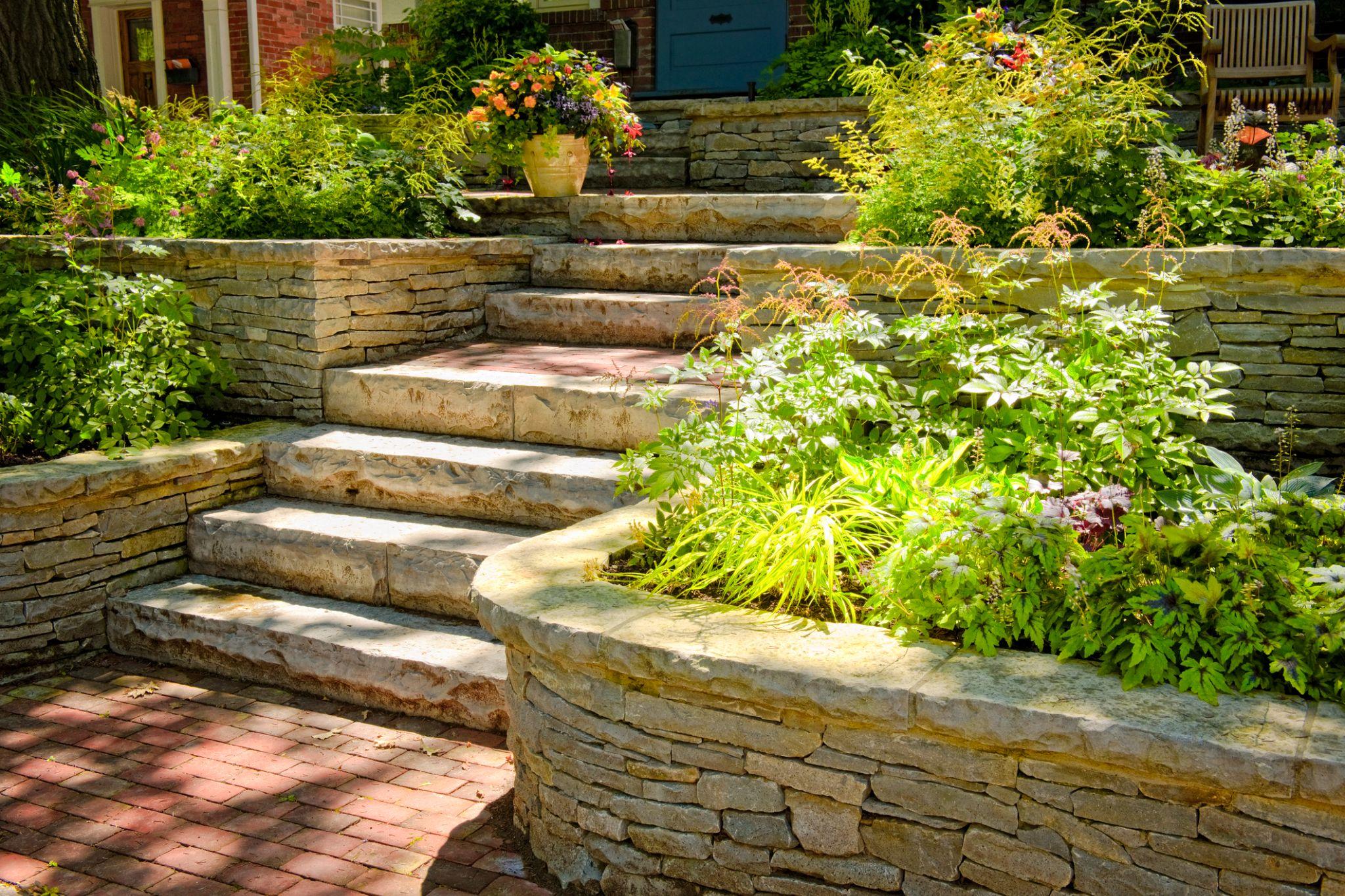 Stone retaining wall with steps and lush garden plantings