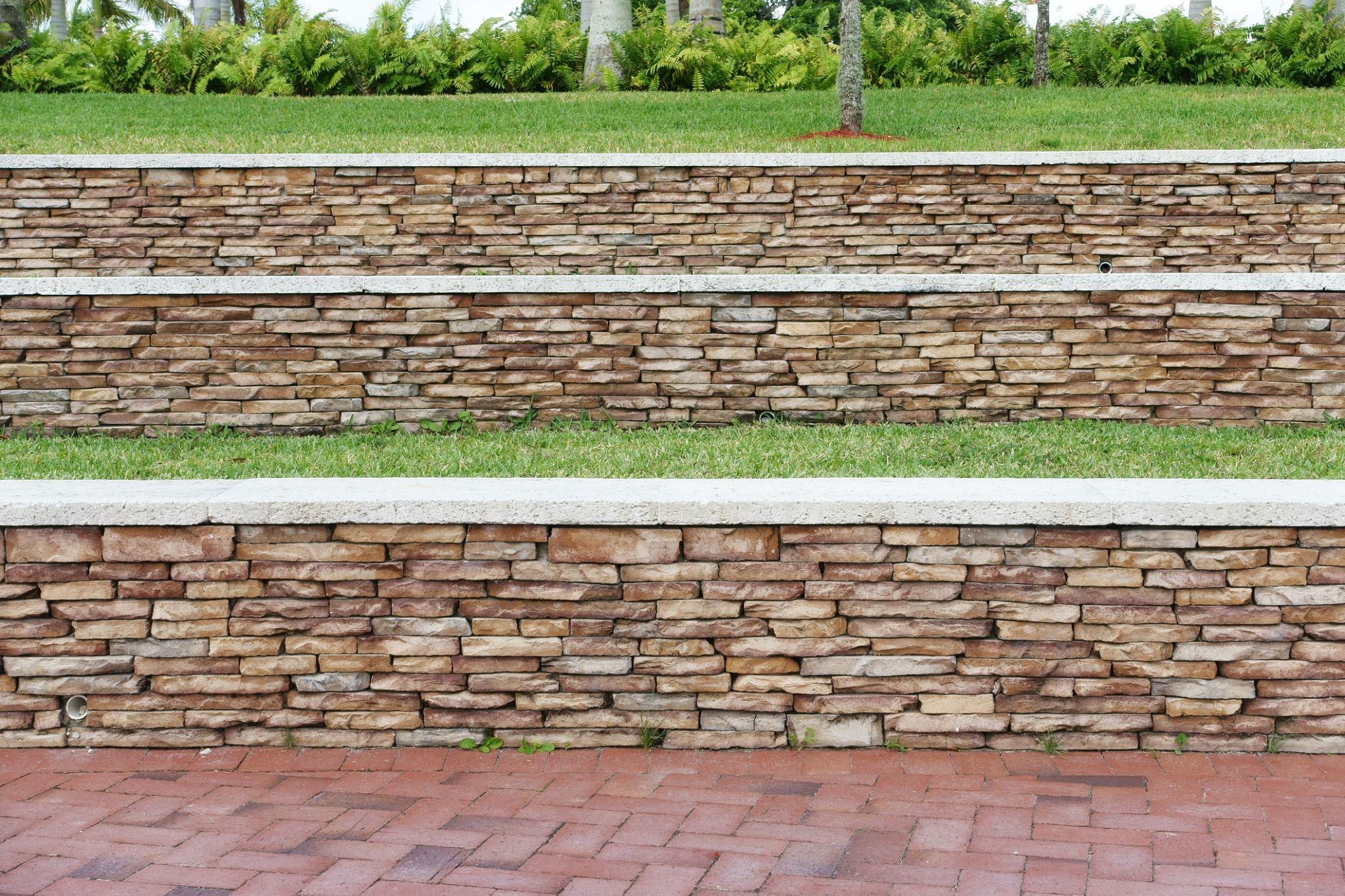 Tiered stone retaining walls with grass terraces and brick paver pathway